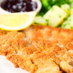 Close-up breaded veal Wiener schnitzel served with parsley buttered potatoes and redcurrant jelly.