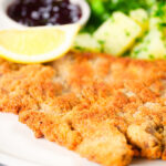 Close-up breaded veal Wiener schnitzel served with parsley buttered potatoes and redcurrant jelly.