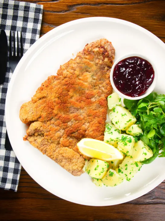 Overhead breaded veal Wiener schnitzel served with parsley buttered potatoes and redcurrant jelly.
