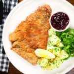 Overhead breaded veal Wiener schnitzel served with parsley buttered potatoes and redcurrant jelly.