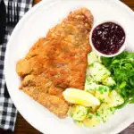 Overhead breaded veal Wiener schnitzel served with parsley buttered potatoes and redcurrant jelly.