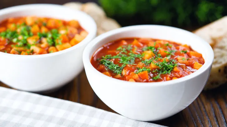 Chunky winter root vegetable soup served with bread and fresh parsley.