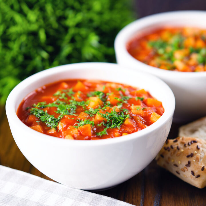 Chunky winter root vegetable soup served with bread and fresh parsley.