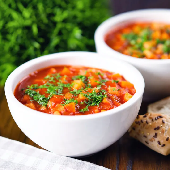 Chunky winter root vegetable soup served with bread and fresh parsley.