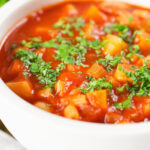 Close-up vegetarian winter root vegetable soup served with fresh parsley.
