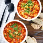 Overhead vegetarian winter root vegetable soup served with bread and fresh parsley.
