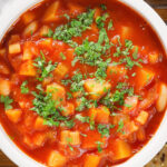 Overhead close-up vegetarian winter root vegetable soup served with fresh parsley.