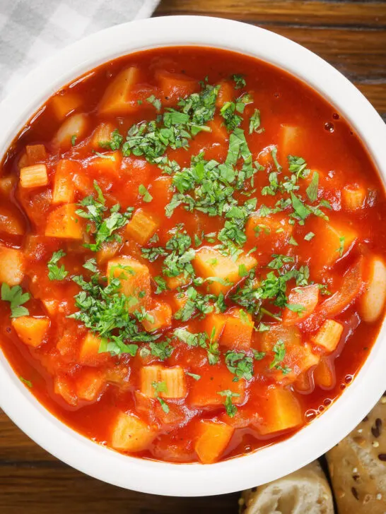 Overhead close-up vegetarian winter root vegetable soup served with fresh parsley.