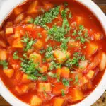Overhead close-up vegetarian winter root vegetable soup served with fresh parsley.