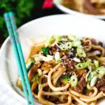 Beef yaki udon, stir fry noodles garnished with spring onions and sesame seeds.