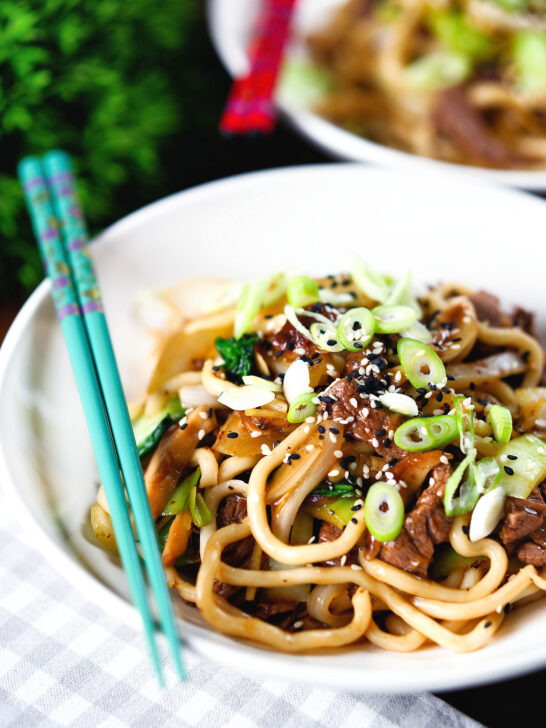 Beef yaki udon, stir fry noodles garnished with spring onions and sesame seeds.
