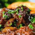 Close-up Belgian carbonnade flamande (beef, onion and beer stew) served with chips.