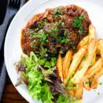 Overhead Belgian carbonnade flamande (beef, onion and beer stew) served with chips.