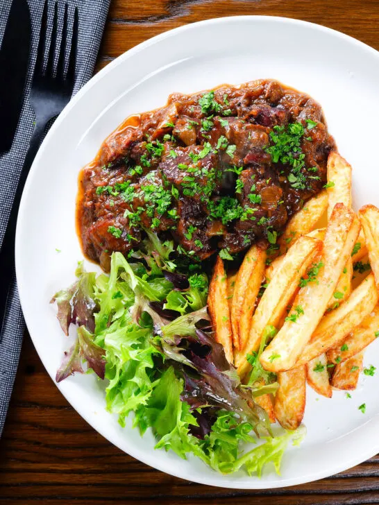 Overhead Belgian carbonnade flamande (beef, onion and beer stew) served with chips.