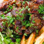 Overhead close-up Belgian carbonnade flamande (beef, onion and beer stew) served with chips.
