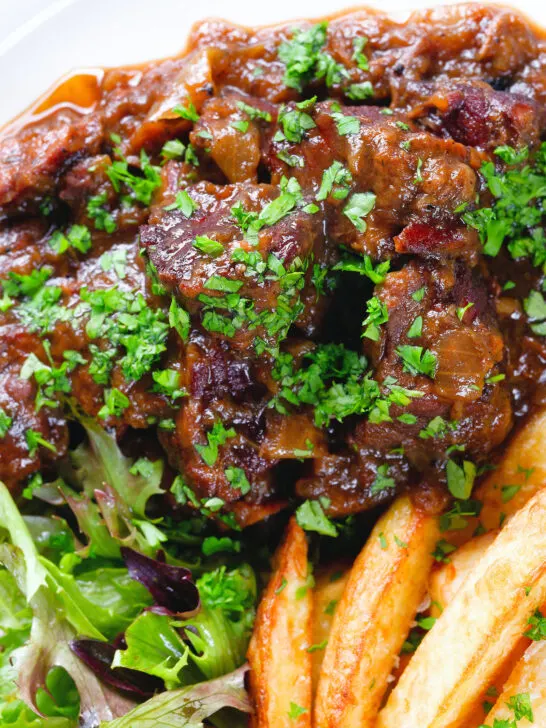 Overhead close-up Belgian carbonnade flamande (beef, onion and beer stew) served with chips.