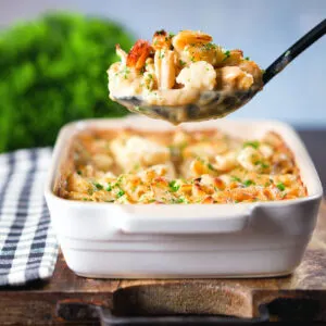 Cauliflower cheese pasta bake with cheddar and stilton on a serving spoon.