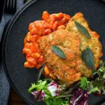 Overhead breaded and fried chicken Milanese served with Italian inspired fagioli all'uccalletto.