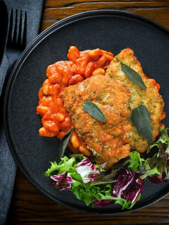 Overhead breaded and fried chicken Milanese served with Italian inspired fagioli all'uccalletto.