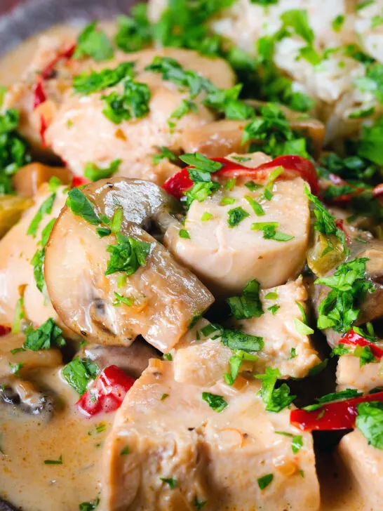 Close-up creamy chicken a la king served with brown rice and parsley.