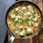 Overhead creamy chicken a la king served with fresh parsley in its cooking pan.