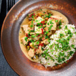 Overhead creamy chicken a la king served with brown rice and parsley.
