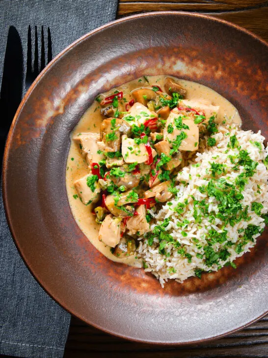 Overhead creamy chicken a la king served with brown rice and parsley.