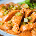Close-up chicken and mushroom stroganoff served with chopped gherkins.