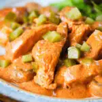 Close-up chicken and mushroom stroganoff served with chopped gherkins.