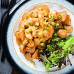 Overhead chicken and mushroom stroganoff served with fried potatoes and chopped gherkins.