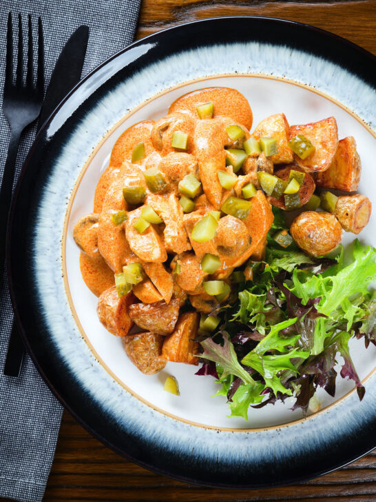 Overhead chicken and mushroom stroganoff served with fried potatoes and chopped gherkins.