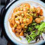 Overhead chicken and mushroom stroganoff served with fried potatoes and chopped gherkins.