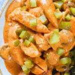 Overhead close-up chicken and mushroom stroganoff served with fried potatoes and chopped gherkins.