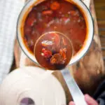 Overhead Greek beef and tomato stew (kokkinisto) being served with a ladle.
