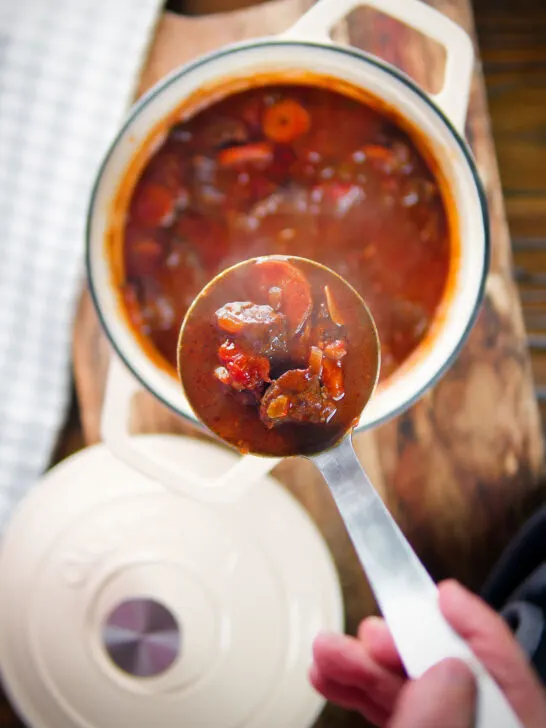 Overhead Greek beef and tomato stew (kokkinisto) being served with a ladle.
