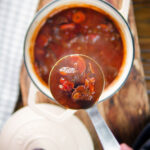 Overhead Greek beef and tomato stew (kokkinisto) being served with a ladle.