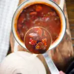 Overhead Greek beef and tomato stew (kokkinisto) being served with a ladle.