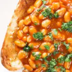 Overhead close-up Indian-inspired spicy masala baked beans on toast with fresh coriander.