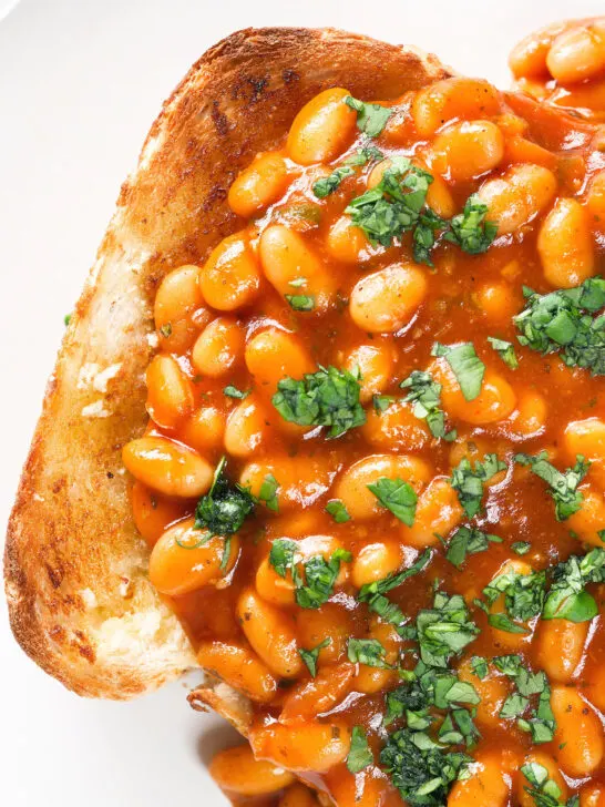 Overhead close-up Indian-inspired spicy masala baked beans on toast with fresh coriander.