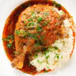 Overhead close-up poulet au vinaigre, chicken legs in garlic and vinegar served with celeriac mash.