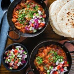 Overhead rajma masala (kidney bean curry) served with kachumber salad and homemade chapatis.