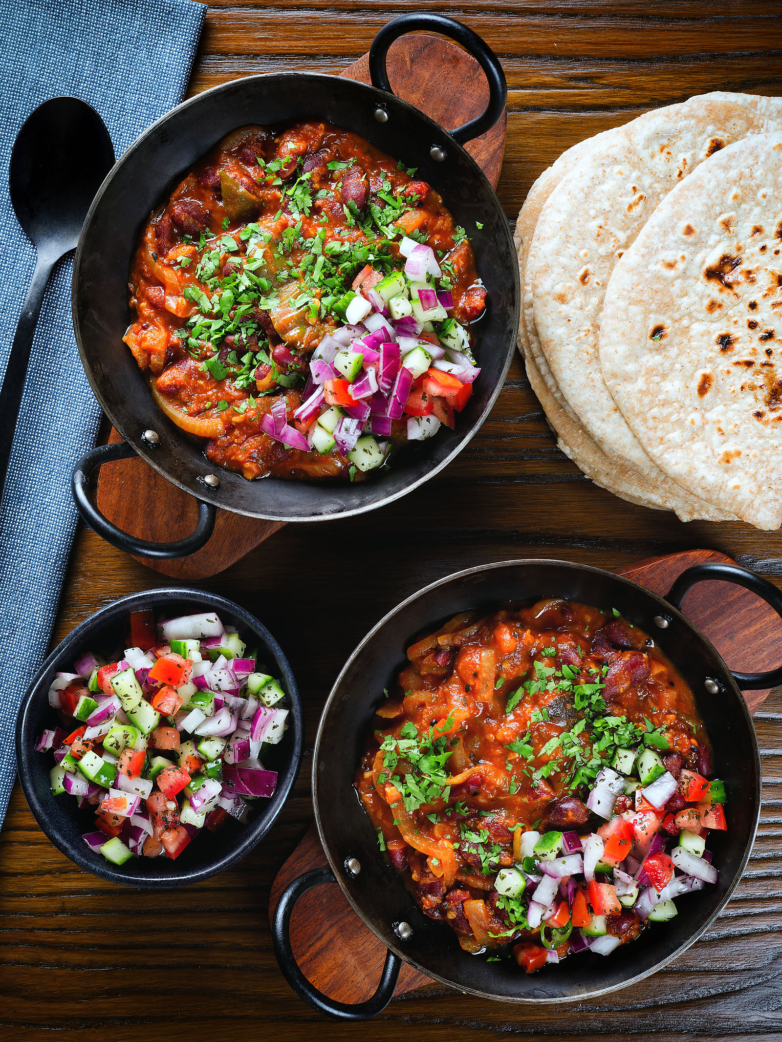 Overhead rajma masala (kidney bean curry) served with kachumber salad and homemade chapatis.
