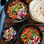Overhead rajma masala (kidney bean curry) served with kachumber salad and homemade chapatis.