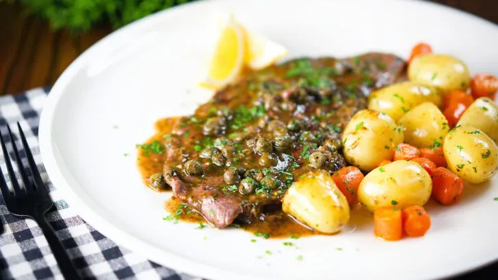 Rose veal scallopini with lemon and capers served with buttered potatoes and carrots.