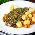 Rose veal scallopini with lemon and capers served with buttered potatoes and carrots.