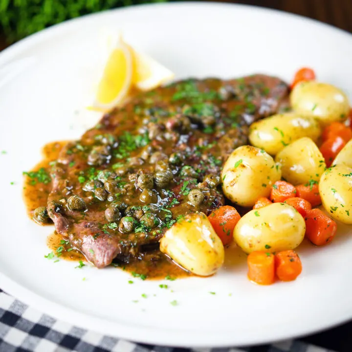 Rose veal scallopini with lemon and capers served with buttered potatoes and carrots.