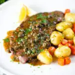 Rose veal scallopini with lemon and capers (piccata) served with buttered potatoes and carrots.
