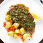 Overhead rose veal scallopini with lemon and capers (piccata) served with buttered potatoes and carrots.