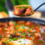 Sausage, bacon, black pudding and baked bean breakfast casserole on a spoon.