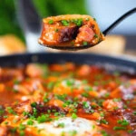 Sausage, bacon, black pudding and baked bean breakfast casserole on a spoon.